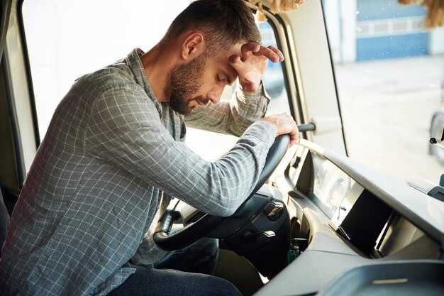 Foto zit binnen moe jonge vrachtwagenchauffeur in casual kleding