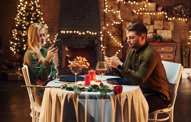 Zit en gebruikt telefoon Jong mooi stel heeft samen romantisch diner binnenshuis