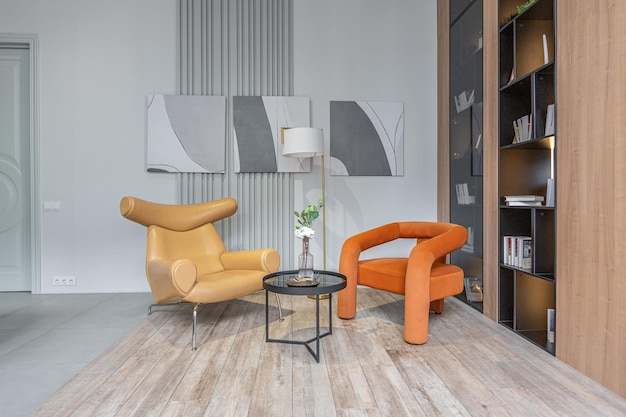 zitkamer met twee zachte stijlvolle fauteuils in een enorm modern ruim appartement met hoge loft stijl plafonds houten decoratie en grijze muren