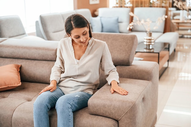 Zitten en ontspannen Vrouw bezoekt beddenwinkel Op zoek naar comfortabele bank