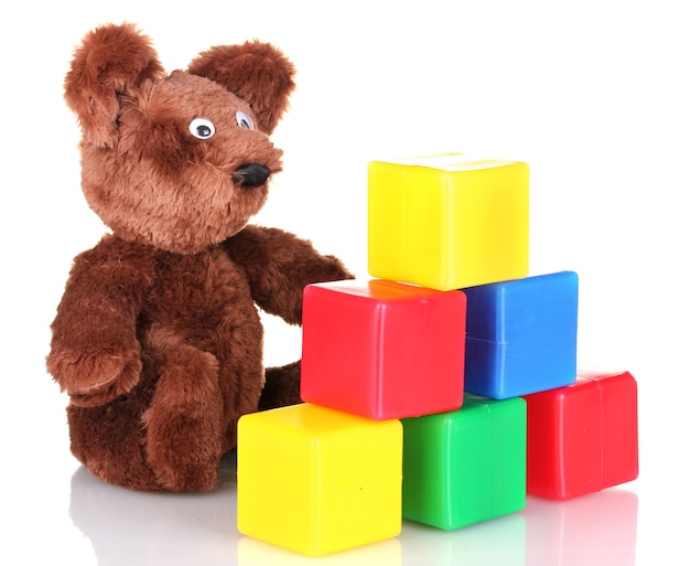 Zittend beer speelgoed en kleurkubussen geïsoleerd op wit