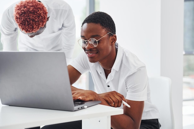 Zittend met laptop Groep Afro-Amerikaanse zakenmensen die samen op kantoor werken
