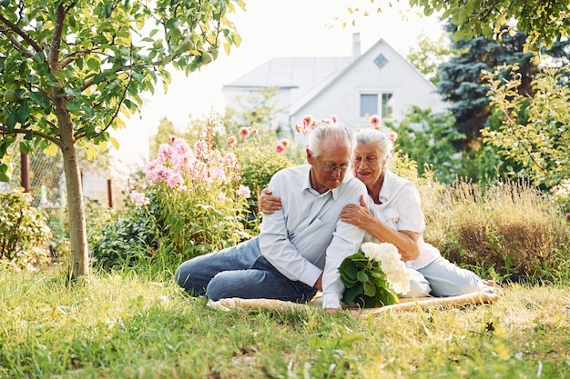 Zittend op de grond Mooi seniorenpaar zit samen in de tuin