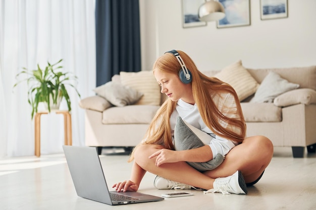 Zittend op de vloer Vrouwelijke tiener met blond haar is overdag thuis