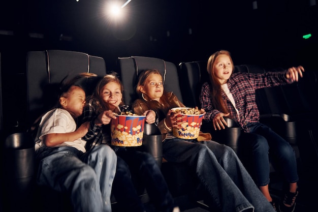 Zittend op de zwarte stoelen Groep kinderen die in de bioscoop zitten en samen film kijken