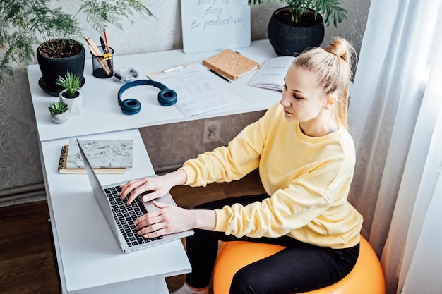 Zittend op een gymbal op het werk gebruik een oefenbal als een stoel op de werkplek freelancer vrouw zit op