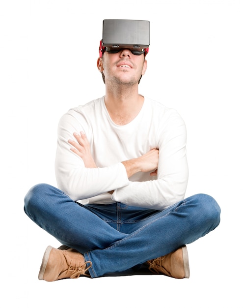 Zittende jonge man met behulp van een virtuele werkelijkheid bril