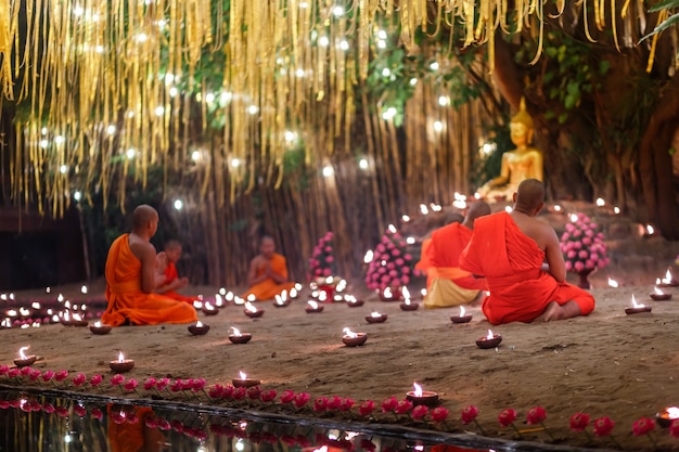 Zittende monniken mediteren met veel kaarsen in de Thaise tempel 's nachts
