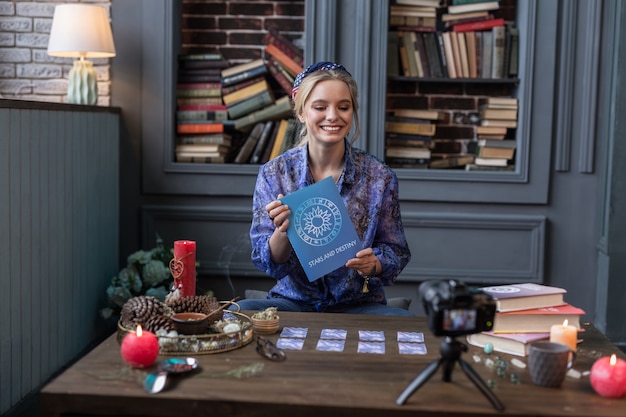 Foto zo behulpzaam. vrolijke aantrekkelijke vrouw die haar favoriete boek vasthoudt terwijl ze het aan de kijkers laat zien