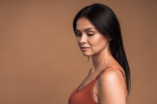 Zo gevoelig. Licht portret van de brunette vrouw met blote schouders en naakt make-up poseren in de studio met beige achtergrond. Schoonheidsconcept