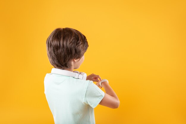 Zo slim. schattige donkerharige jongen die en op zijn horloge denkt te kijken