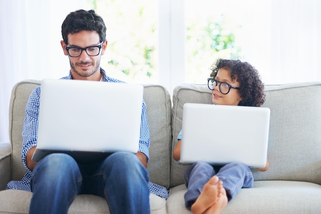 Zo vader zo zoon Shot van een vader en zoon die laptops gebruiken op de bank in de woonkamer