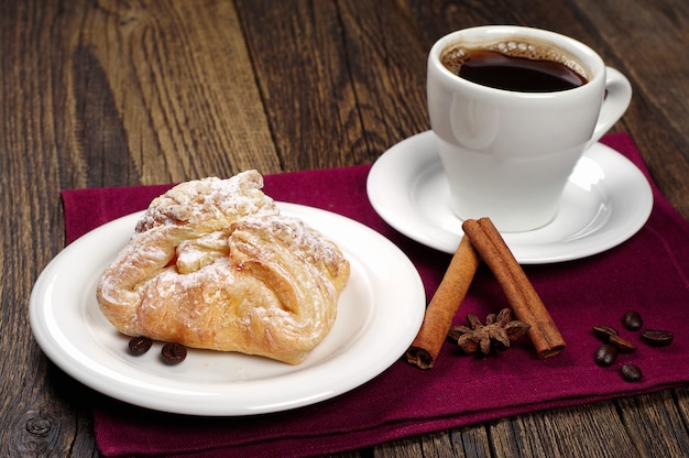 Zoet broodje en kopje koffie op houten tafel