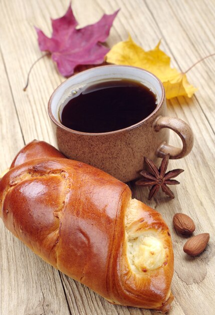 Zoet broodje en kopje koffie op tafel