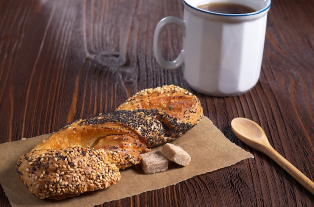 Zoet broodje met lijnzaad en maanzaad en kopje thee op tafel