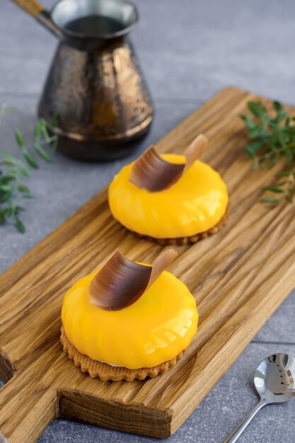 Zoet dessert Gele perzikcakes met plakje chocolade bovenop op houten snijplank en cezve