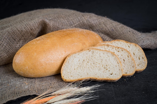 Zoet lekker brood en tarwe op houten achtergrond