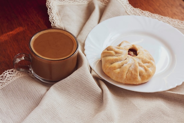 Zoet ontbijt, koffie met melk en een broodje op een servet op tafel