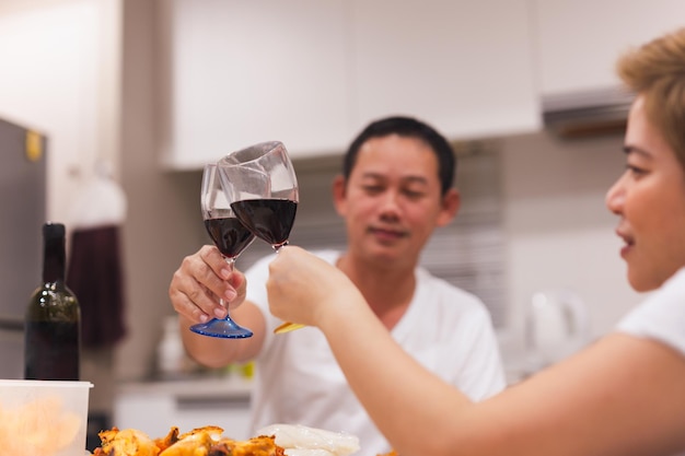 Zoet paar dat diner met het roosteren van glazen rode wijn thuis heeft