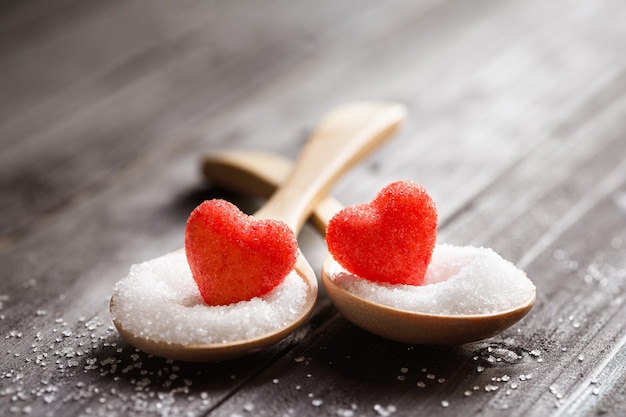 Foto zoet rood snoepje in de vorm van een hartpaar op een houten suikerlepel