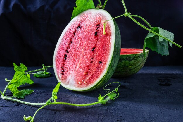 Zoet water meloenfruit in tweeën gesneden op een zwarte achtergrond.