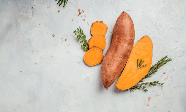 Zoete biologische oranje aardappel op lichte achtergrond. lang bannerformaat. bovenaanzicht.