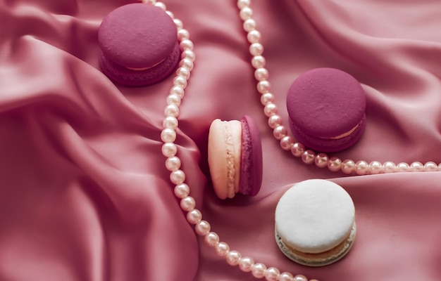 Zoete bitterkoekjes en parels sieraden op zijde achtergrond Parijse chique sieraden Franse dessert eten en cake macaron voor luxe zoetwaren merk vakantie cadeau