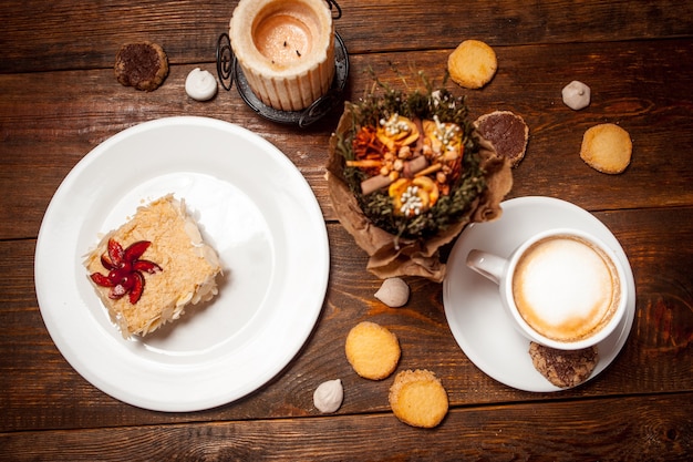 Zoete cake en cappuccino op feestelijke houten tafel