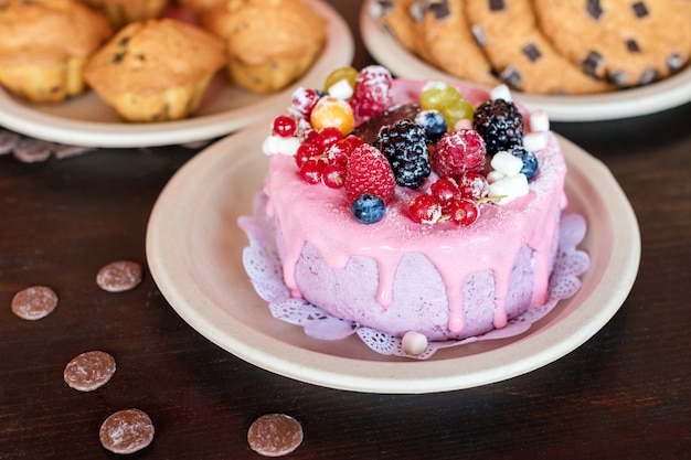 Zoete cheesecake met verse bessen en yoghurtroom. Heerlijke frambozen cake met verse aardbeien, frambozen, bosbessen, krenten en bramen fruit op rustieke houten oppervlak