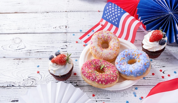 Zoete cupcakes en donuts met de vlag van de vs op houten achtergrond