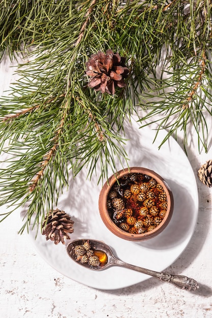 Zoete dennenappeljam. traditioneel siberisch dessert, verse groenblijvende takken. trendy hard licht, donkere schaduw. witte houten achtergrond, bovenaanzicht