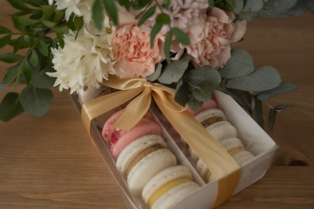 Zoete dessert bitterkoekjes in een doos versierd met lint en bloemen op een houten tafel