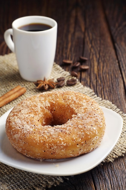 Zoete donut en kopje zwarte koffie op donkere houten tafel