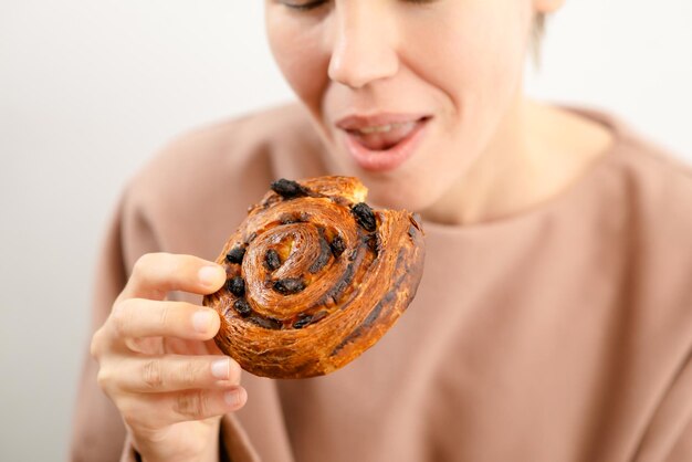 Zoete elegantie Een verleidelijke vrouw in haar bloei geniet van een rozijn gevulde broodje genieten van de zoete elegantie van haar dessert