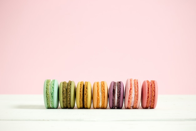 Zoete en kleurrijke Franse makarons of macaron op witte houten lijst roze achtergrond, Dessert.