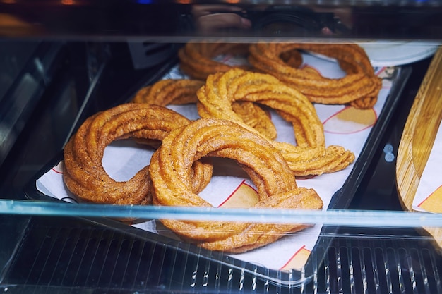 Zoete gebakken churros-krakeling met kaneel en karamel op de toonbank in straatcafé