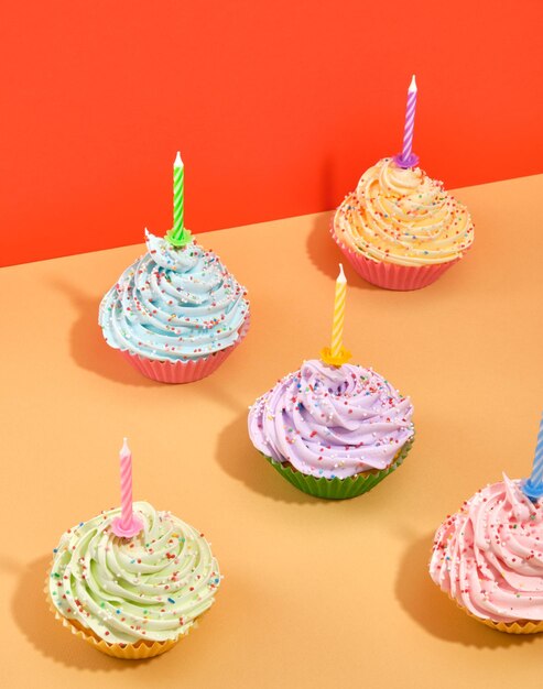 Zoete goede aantrekkelijke verse veelkleurige roomdessert verjaardag cupcakes met vakantiekaarsen Vieringsstemming