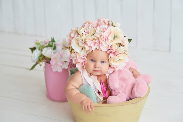 Zoete grappige baby in hoed met bloemen. Pasen. Schattige babymeisje 6 maanden met bloem hoed.