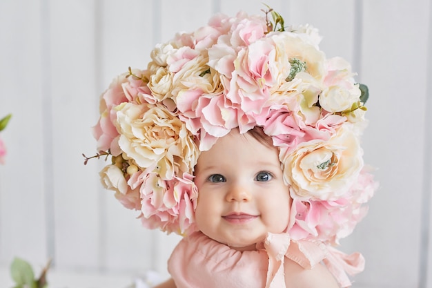 Zoete grappige baby in hoed met bloemen. Pasen. Schattige babymeisje 6 maanden met bloem hoed.