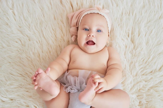 Zoete grappige baby op bed in de kinderkamer. Schattige babymeisje 6 maanden zitten en kruipen.