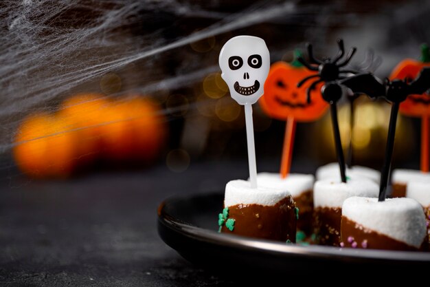 Foto zoete halloween-traktatie met chocolade bedekte marshmallows met suiker en halloween-versieringen op een