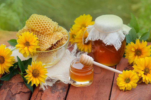 Zoete honing in de kam Potten met honingbij honingraat op houten tafel met bloemenachtergrond Natuurlijk biologisch gezond voedselconcept