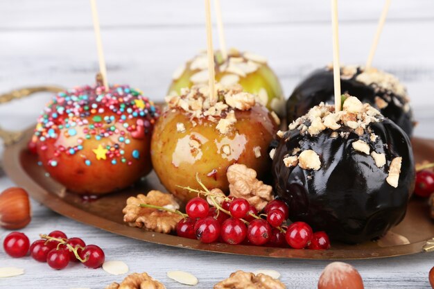 Zoete karamelappels op stokjes met bessen, op houten tafel