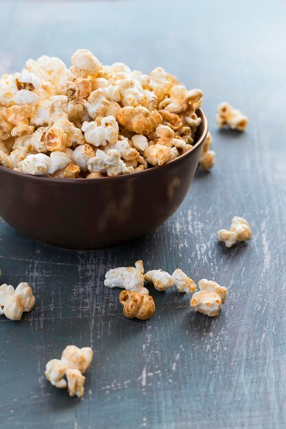 Zoete karamelpopcorn in een kom op een donkerblauwe selectieve nadruk als achtergrond