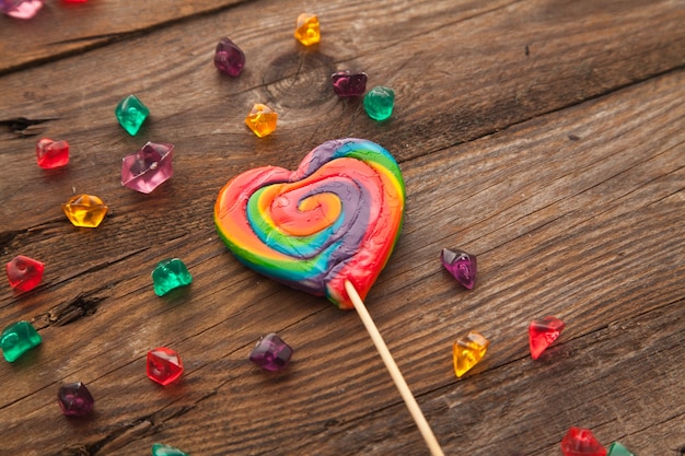 Zoete kleurrijke lolly in de vorm van een hart op houten achtergrond