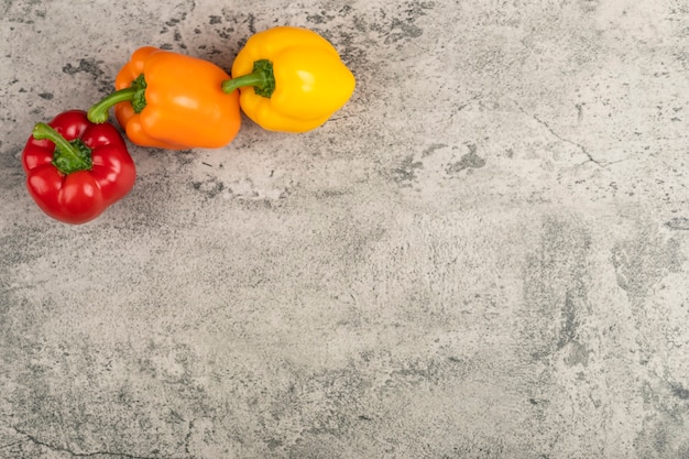 Zoete kleurrijke paprika's die op stenen oppervlak worden geplaatst