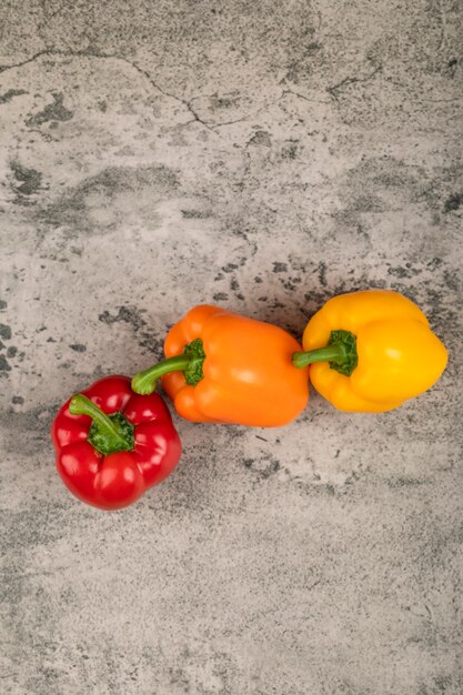 Zoete kleurrijke paprika's die op stenen oppervlak worden geplaatst