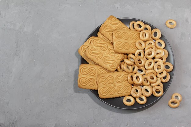 Zoete koekjes en bagels voor thee op een zwarte plaat op een grijze achtergrond