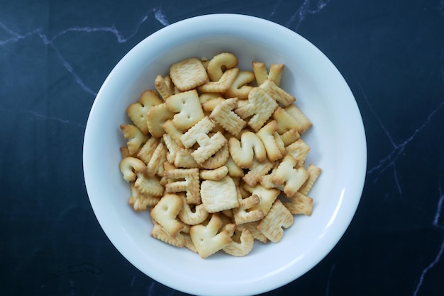 Zoete koekjes in lettervorm in een witte kom op zwart