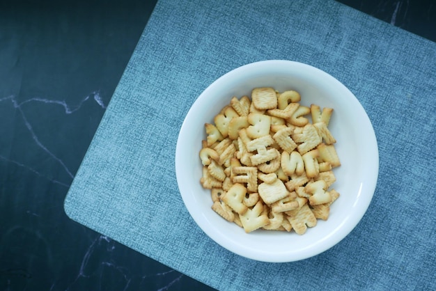 Zoete koekjes in lettervorm in een witte kom op zwart